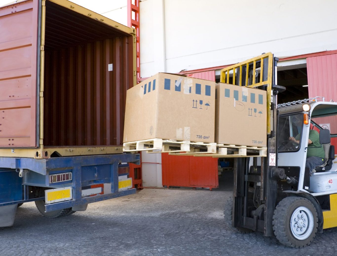 Gabelstapler hebt Kartons aus einem Container in ein Lastfahrzeug.